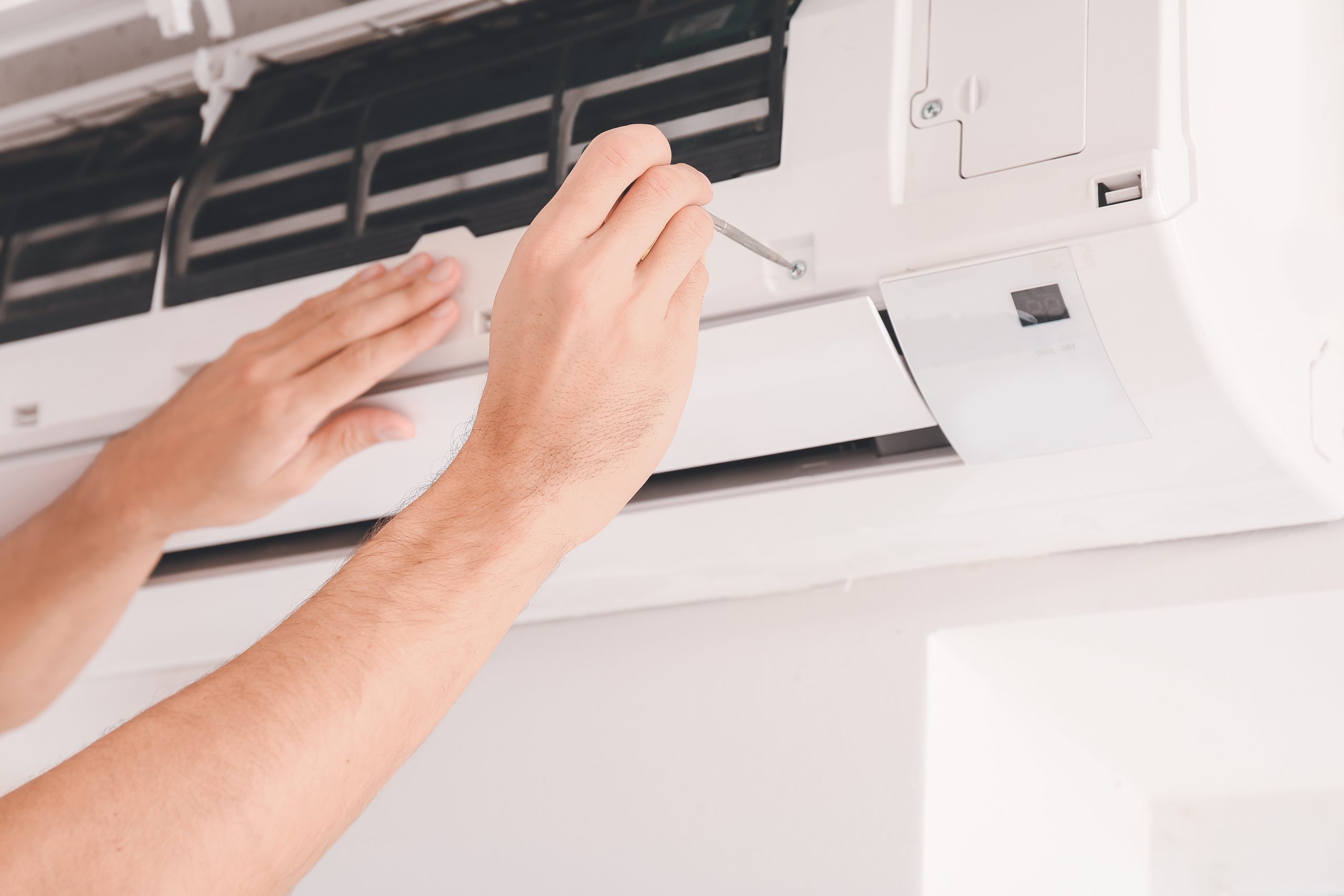Male technician repairing air conditioner indoors