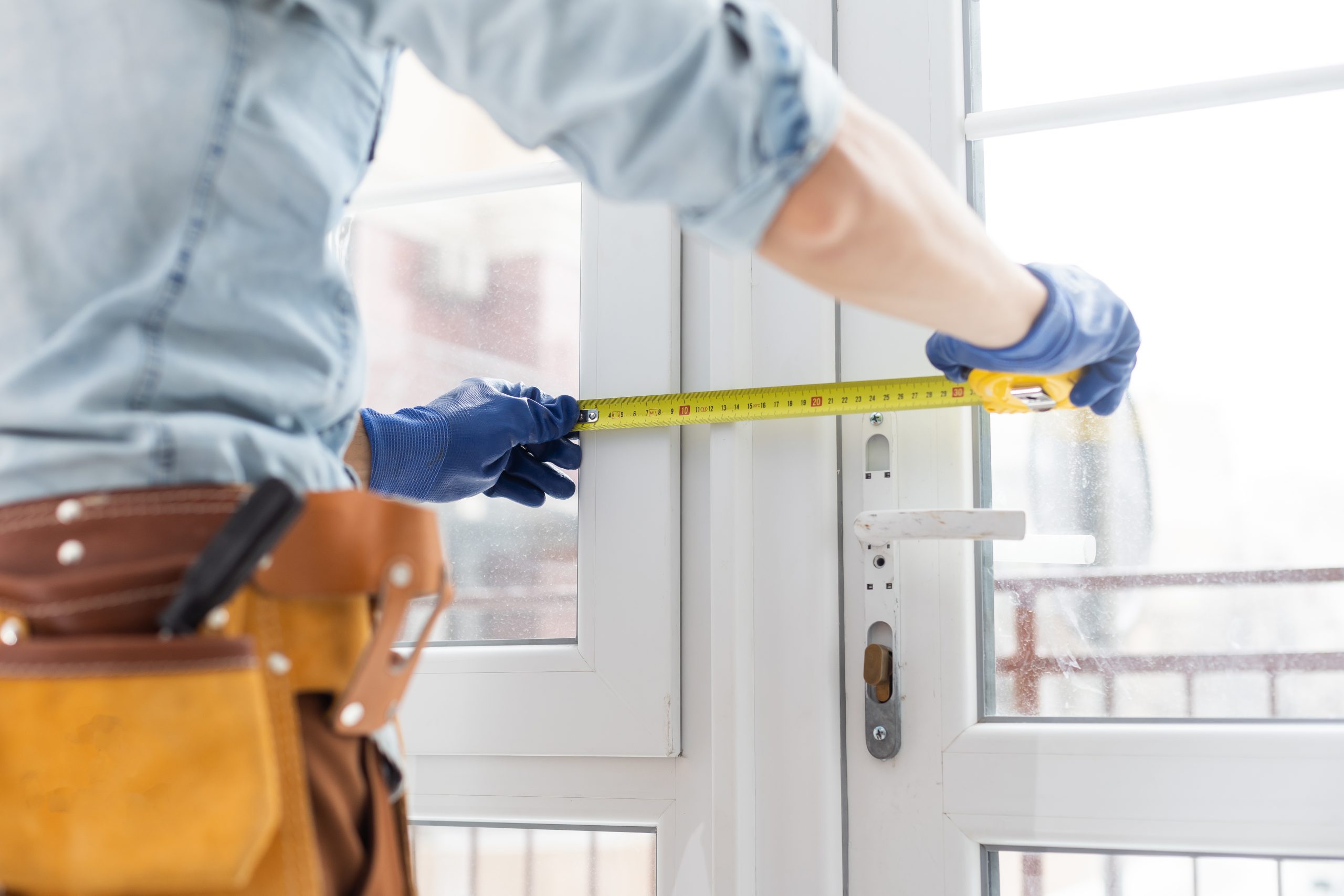handsome young man installing bay window in a new house construction site
